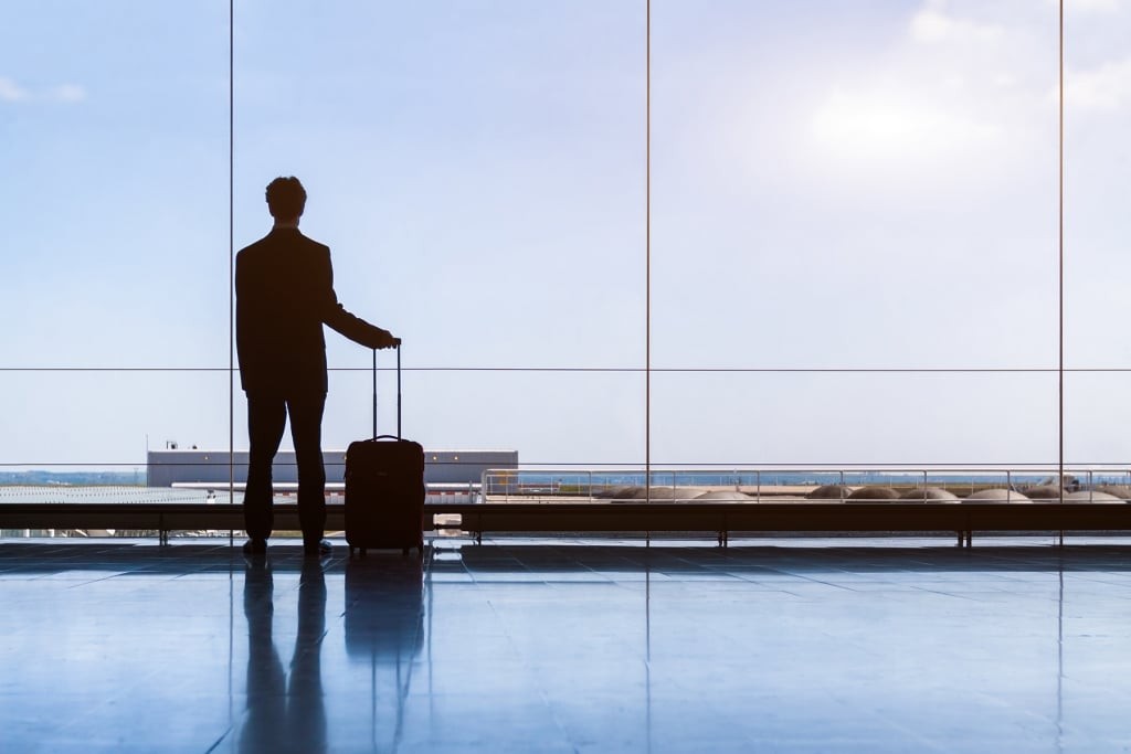 Traveler businessman in airport lounge waiting for flight, stand